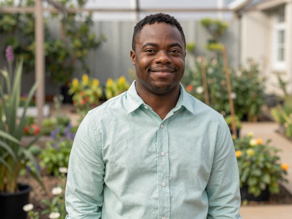 Marcus, an adult with Down syndrome, smiles confidently in a community garden as a member of the down syndrome dating community