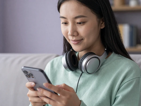 Maya, an autistic woman in mint sweatshirt, smiling at her phone - autism dating app category