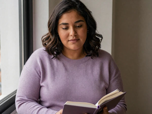 Elena, a woman with bipolar disorder, journaling by a sunlit window - bipolar dating category